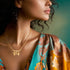 A woman with curly hair is depicted wearing a vibrant floral-patterned blouse featuring a deep neckline. She accessorizes with an elegant Boy and Girl Children Pendant Hearth Necklace for Mother's Day, crafted in 14k gold with intricate designs, set against a soft green backdrop. Her face is partially visible.